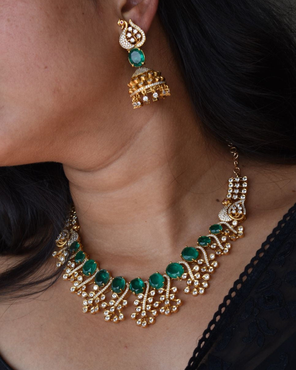 Doublet pendant set with vine-like golden patterns and chandelier jhumkis, angled front view